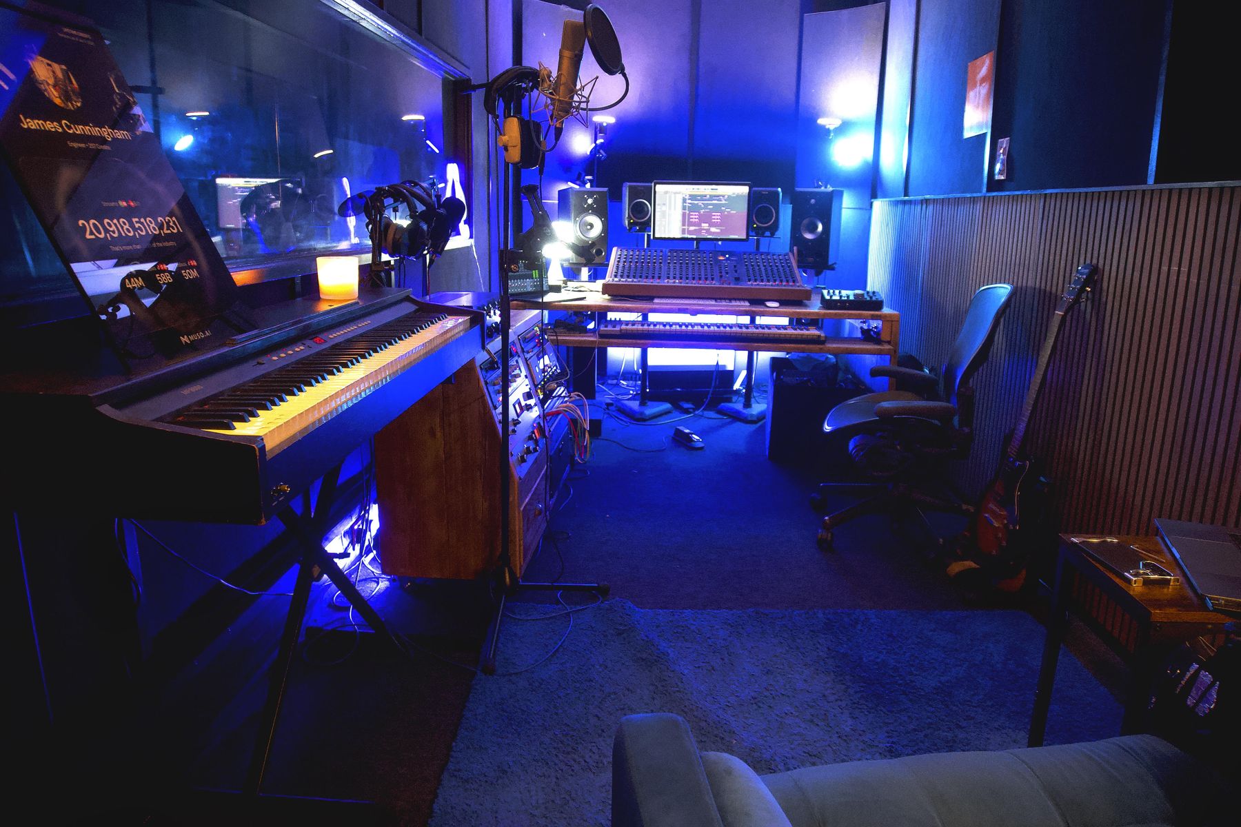 The JC Recording Studios control room in Croydon: analogue mixing desk, studio monitors, keys and a condenser microphone under blue light